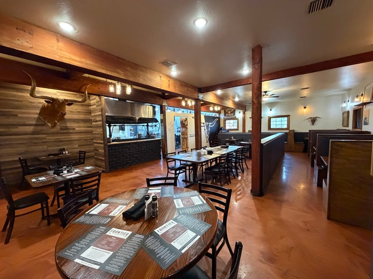 Modern restaurant interior with wooden elements, dining tables, bar counter, and recessed ceiling lights in warm tones