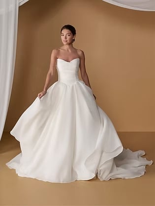 Woman wearing an elegant white ball gown wedding dress with a sweetheart neckline and flowing skirt with train