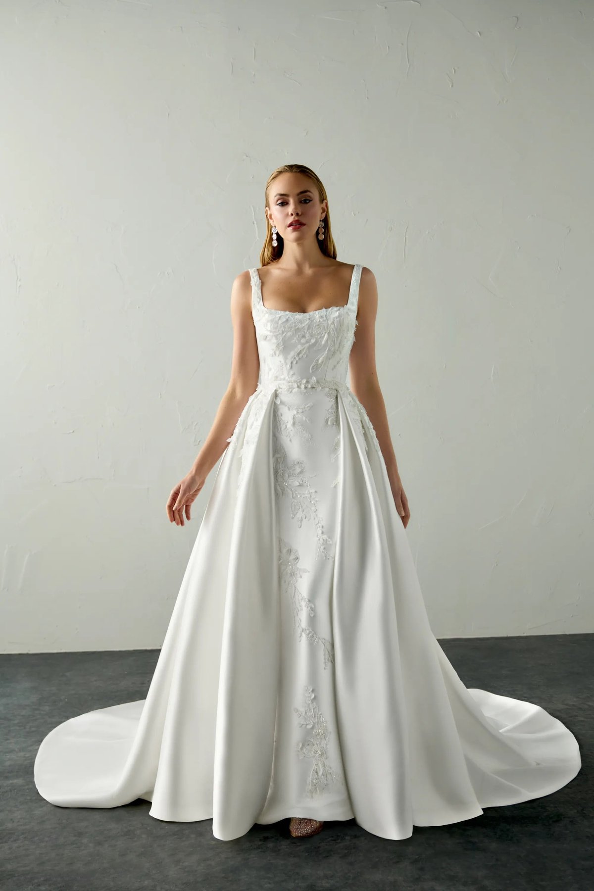 Woman wearing an elegant white sleeveless wedding dress with beaded bodice and flowing skirt with train