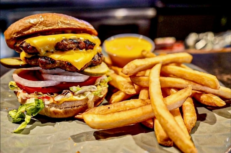 Gourmet double cheeseburger with lettuce and tomato served with crispy golden fries and dipping sauce