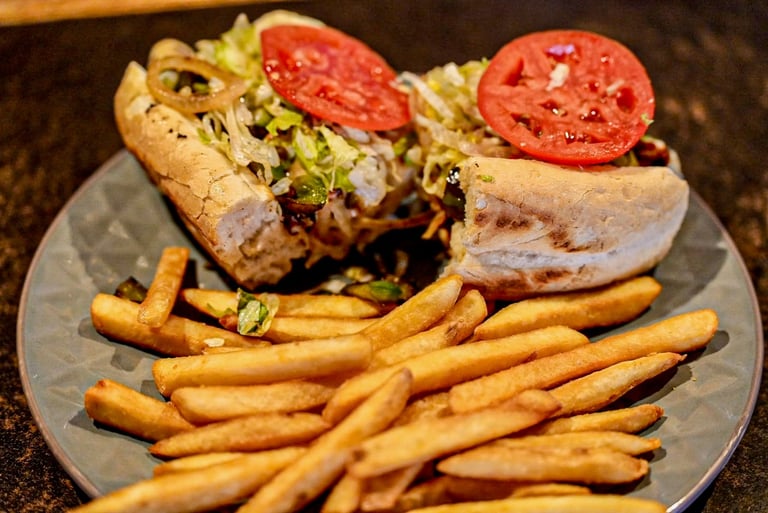 Two sandwiches with tomato and lettuce served with golden french fries on a gray plate