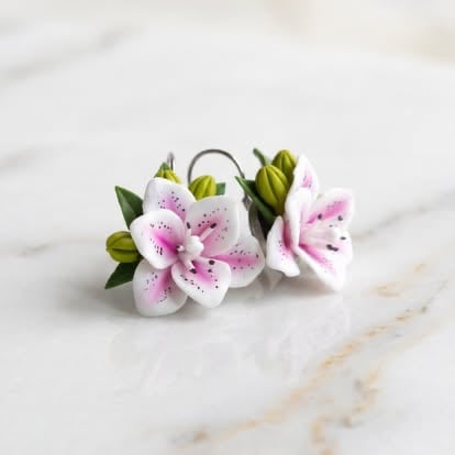 Decorative hair clip with pink and white spotted lily flowers and green leaves on marble background
