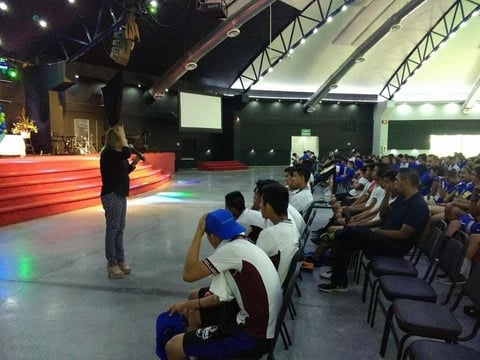 Conferencista presentándose ante el público en evento masivo con escenario rojo