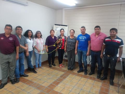 Grupo de once personas en reunión comunitaria con objeto decorativo central