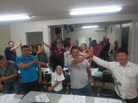 Grupo de personas celebrando con brazos arriba en sala interior
