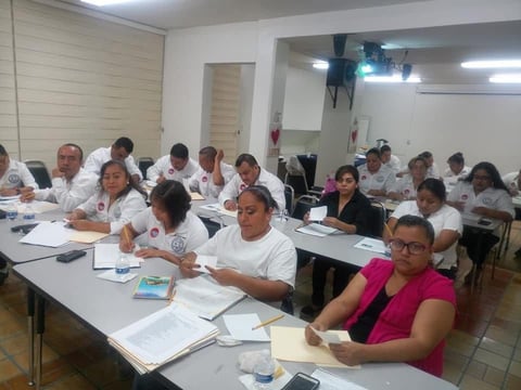 Salón lleno de adultos en playeras blancas durante taller de capacitación
