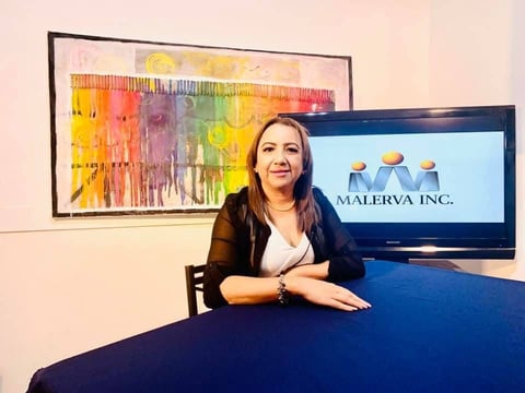 Mujer frente a escritorio con pantalla con logo Malerva Inc.
