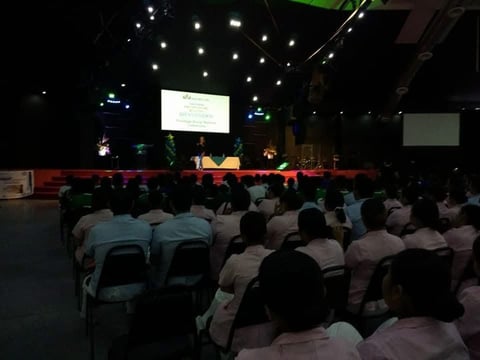 Auditorio lleno durante conferencia con escenario y pantallas