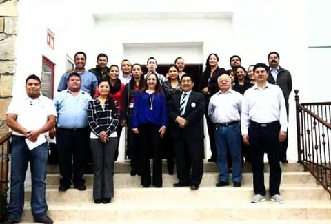 Grupo de personas posando en gradas frente a edificio