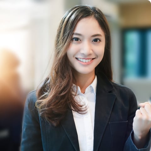Professional woman in business suit and white shirt smiling at camera in office setting