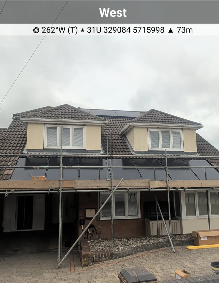 Two-story residential house with solar panels installed on the roof and scaffolding in place for safe professional installation