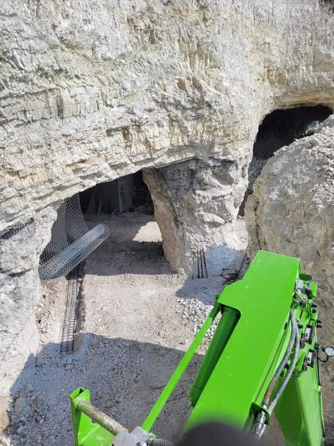 Green bicycle parked at entrance to white chalk cave tunnel with dark openings and stone walls