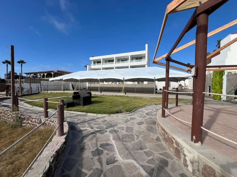 Carpas blancas instaladas en jardín con patio de piedra y pérgola de madera