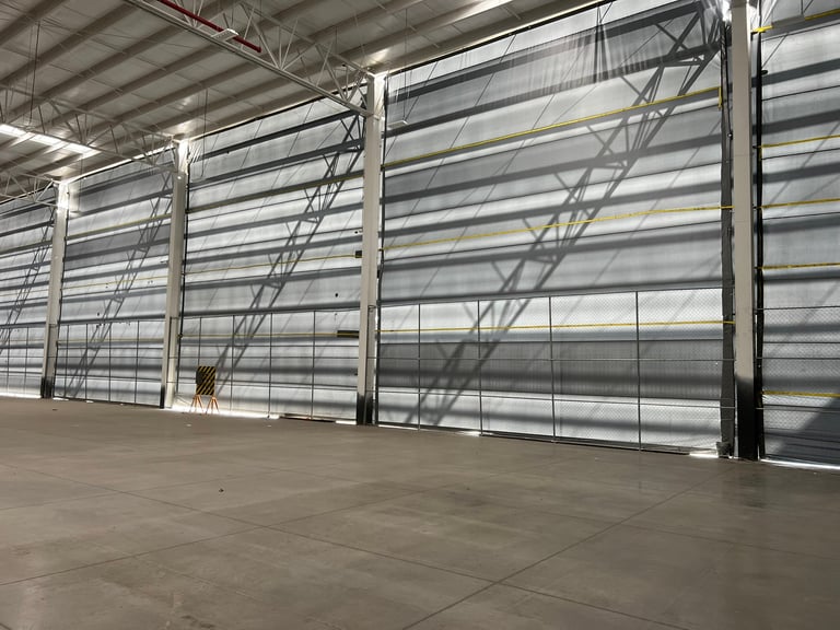 Interior de bodega industrial con tres puertas enrollables de aluminio y piso de concreto