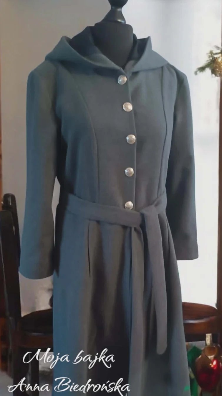 Dark teal hooded dress on mannequin with silver buttons and waist tie belt