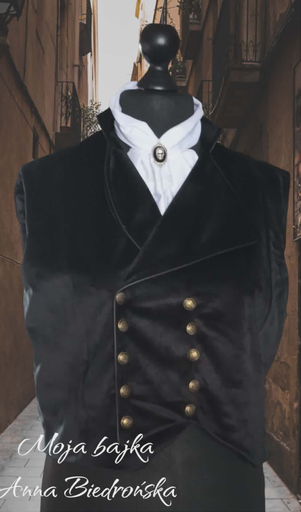 Mannequin dressed in black velvet double-breasted vest with white ruffled collar and cameo brooch, displayed in narrow European alleyway