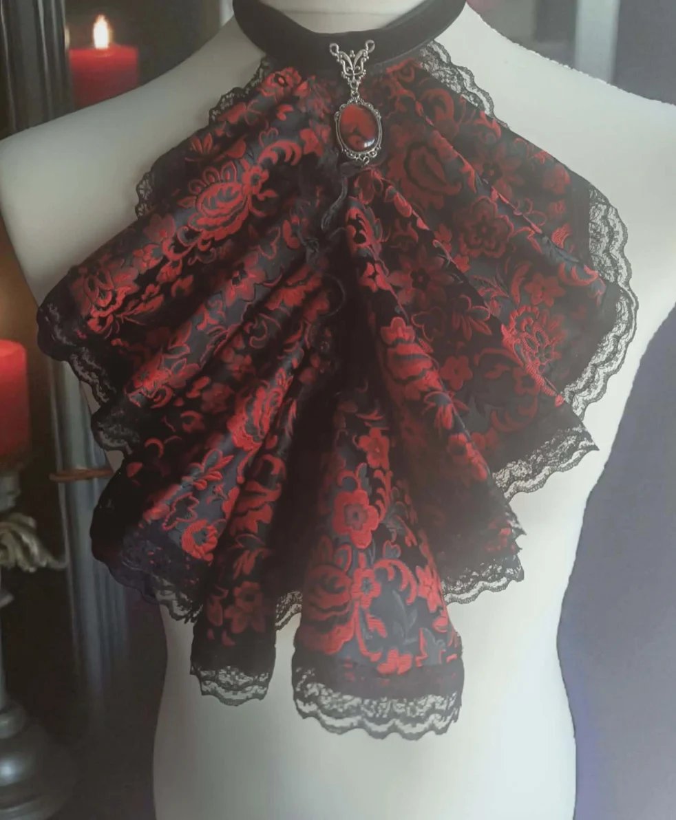 Red and black lace bow accessory displayed on a white mannequin with decorative pendant necklace and red candles visible