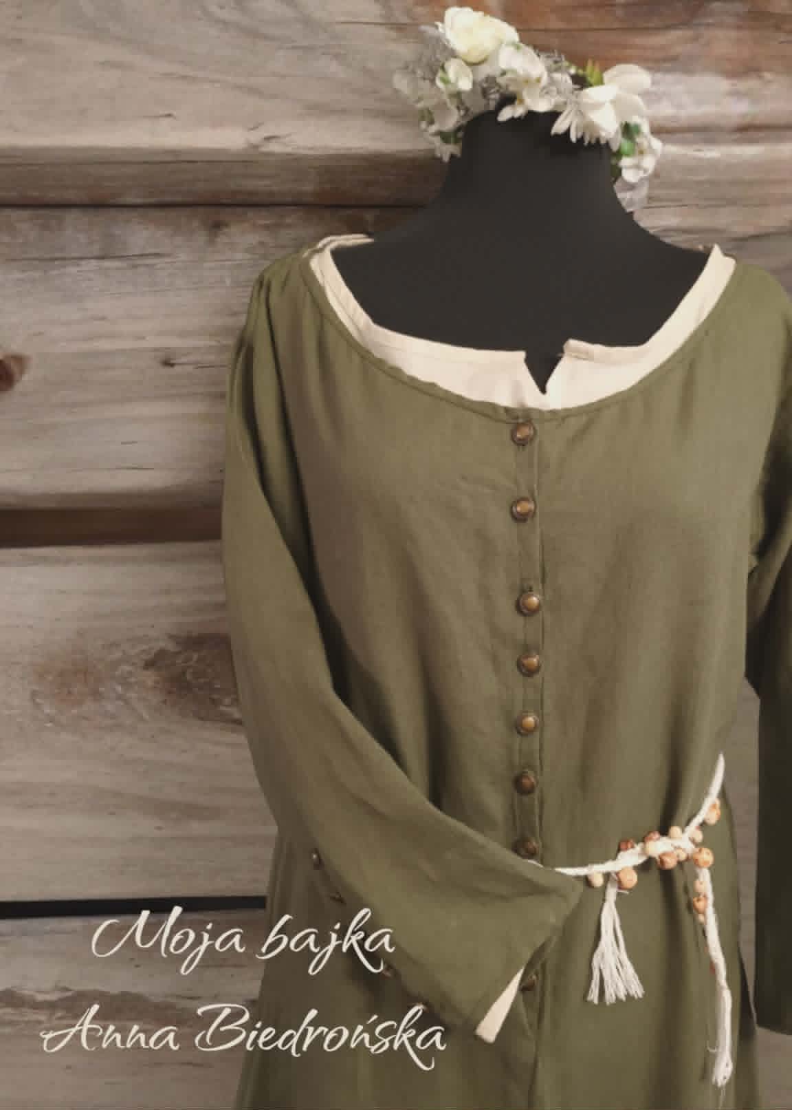 Mannequin wearing olive green historical dress with cream collar, button back detail, and white flower crown and belt tie