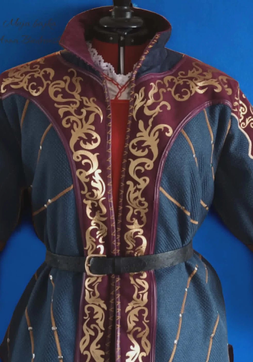 Medieval-style blue robe with ornate gold embroidered trim, burgundy accents, and cinched waist belt displayed on mannequin against blue background