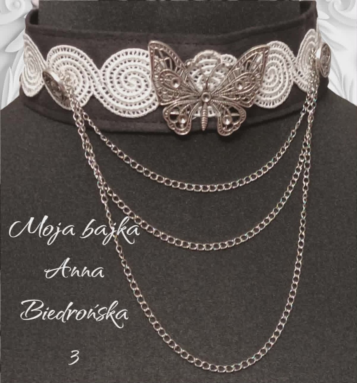 Silver filigree choker with butterfly centerpiece and layered chain drape on dark fabric backdrop