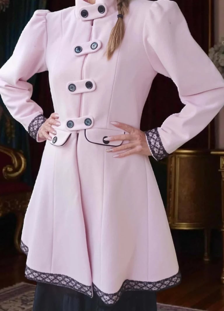 Woman wearing a pink double-breasted coat with puffed sleeves, lace trim, and metal buttons