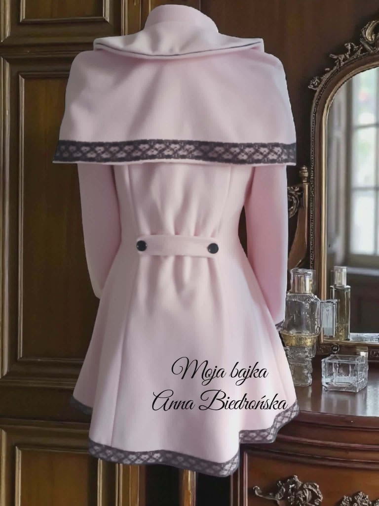 Pink dress on mannequin with decorative collar and script text, displayed in elegant interior with mirror and wooden details
