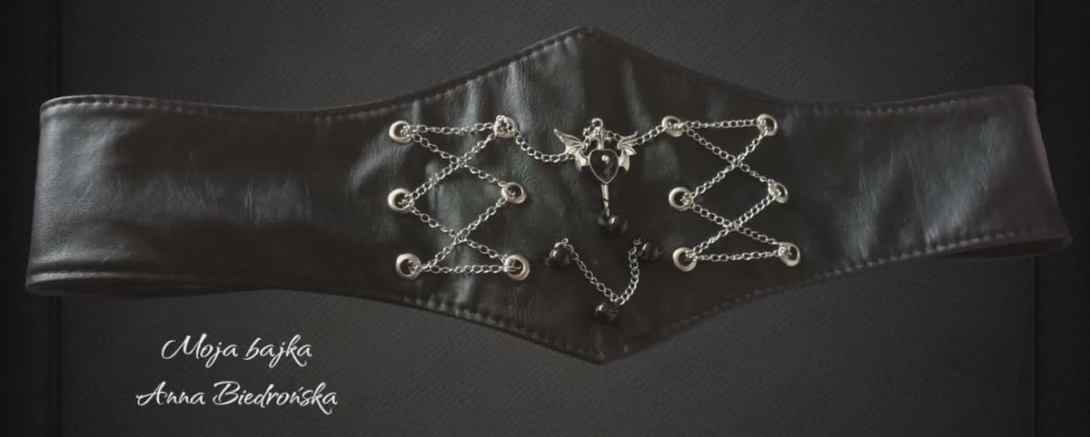 Black leather belt with ornate silver chain and geometric studded design across the front