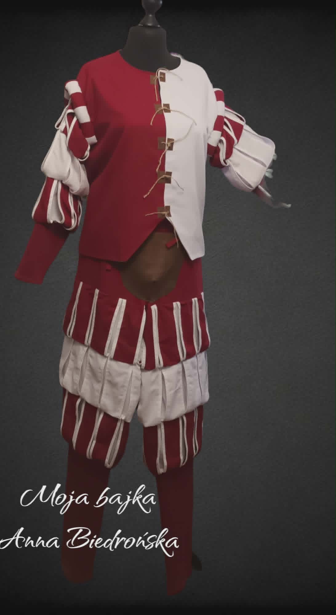 Mannequin wearing traditional Polish folk costume with red and white striped skirt, red vest, and hat against dark background