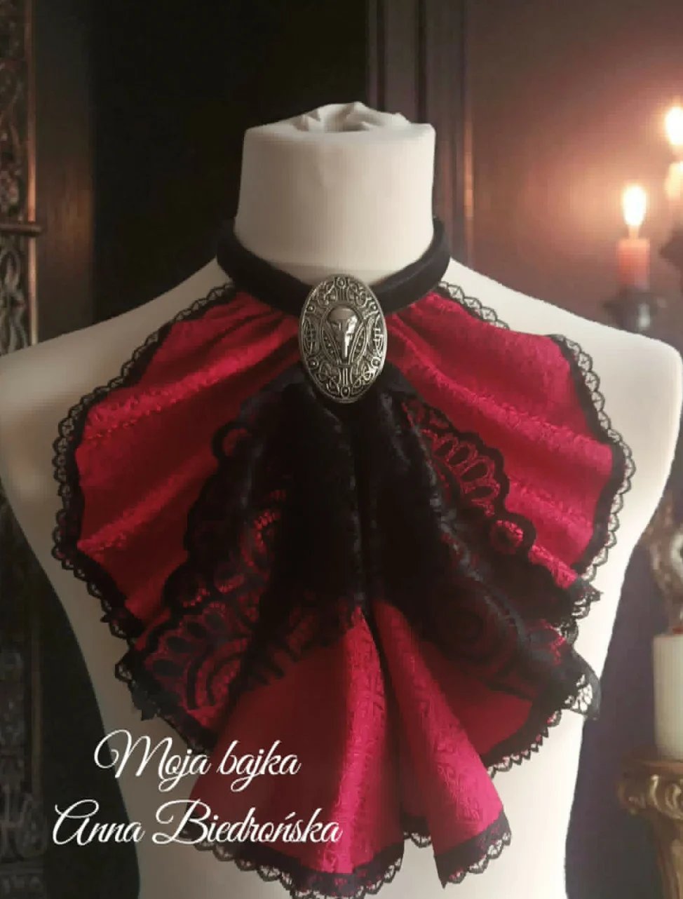 Red and black lace ruffled choker with ornamental silver brooch on white dress form mannequin