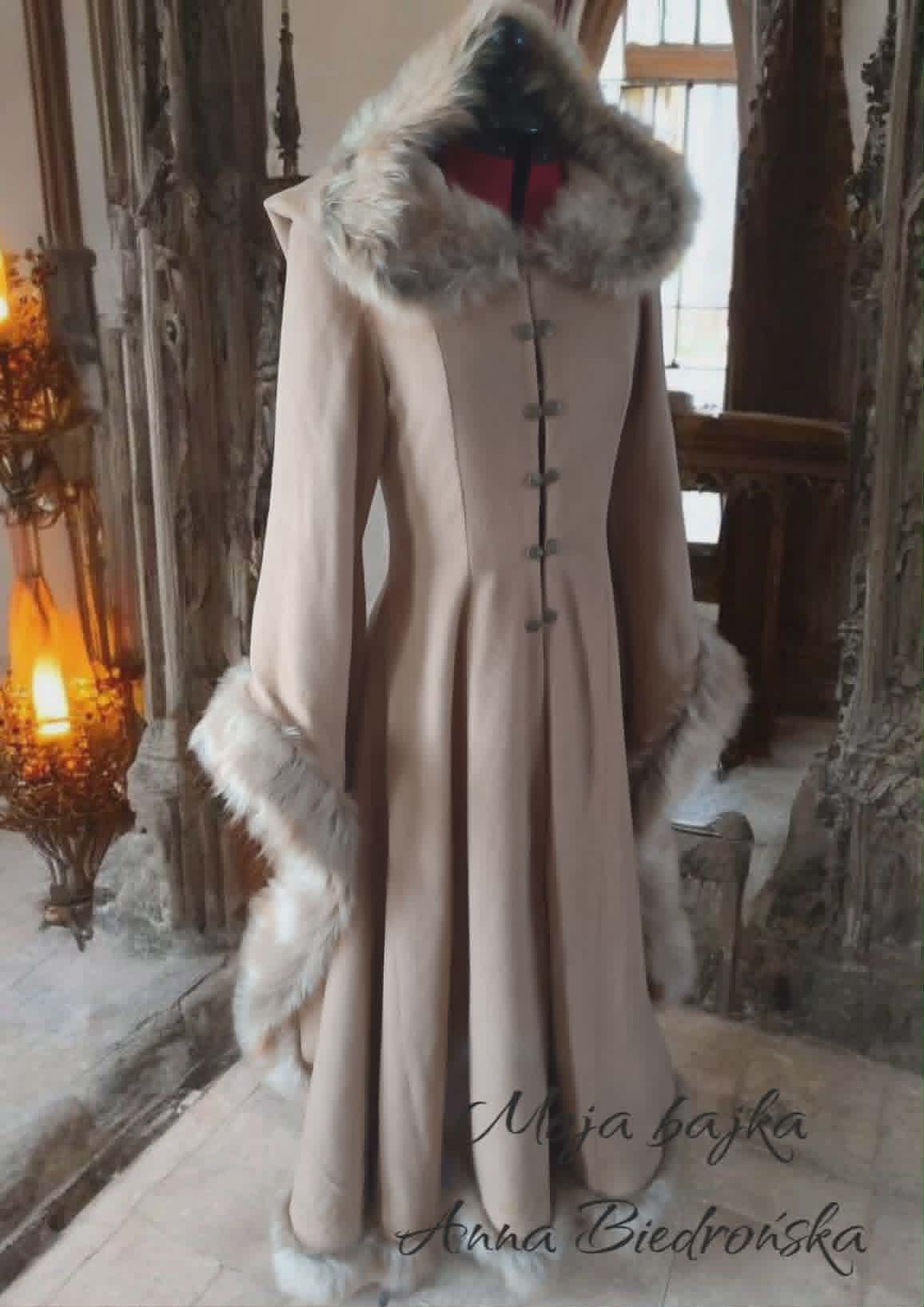 Elegant beige coat with white fur collar and cuffs displayed on a mannequin in a winter holiday setting