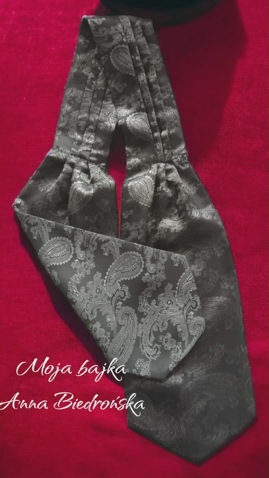 Black paisley patterned silk scarf on pink background with Polish text overlay