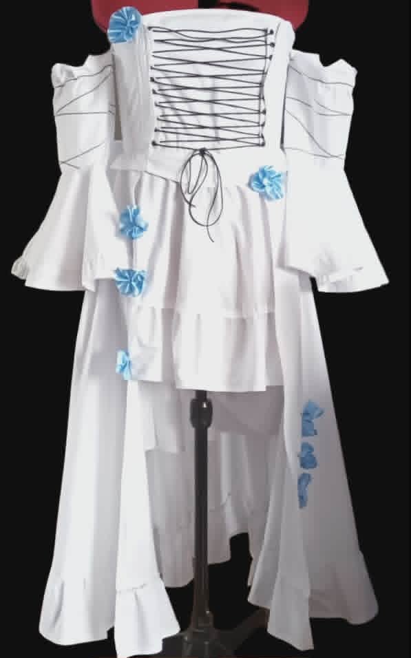White dress with off-shoulder ruffled sleeves, lace-up corset back, and blue flower embellishments on a mannequin against black background