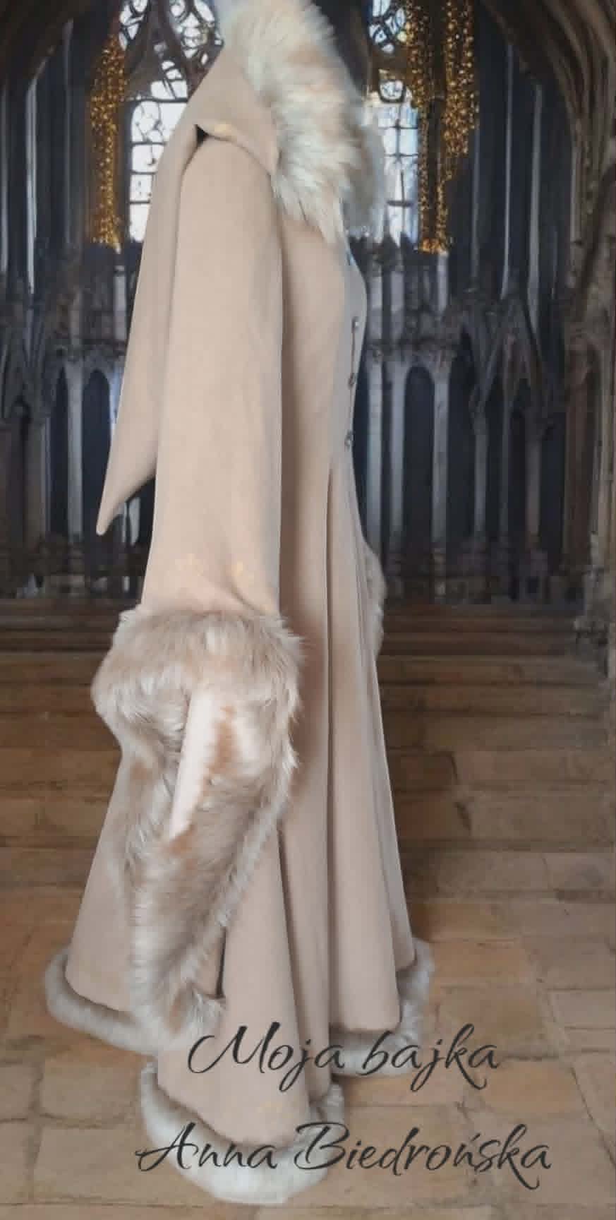 Back view of elegant beige floor-length gown with white fur trim and collar, displayed in ornate cathedral setting