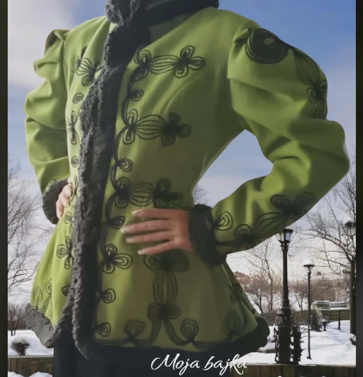 Person wearing a lime green coat with black fleur-de-lis pattern, standing outdoors in winter setting