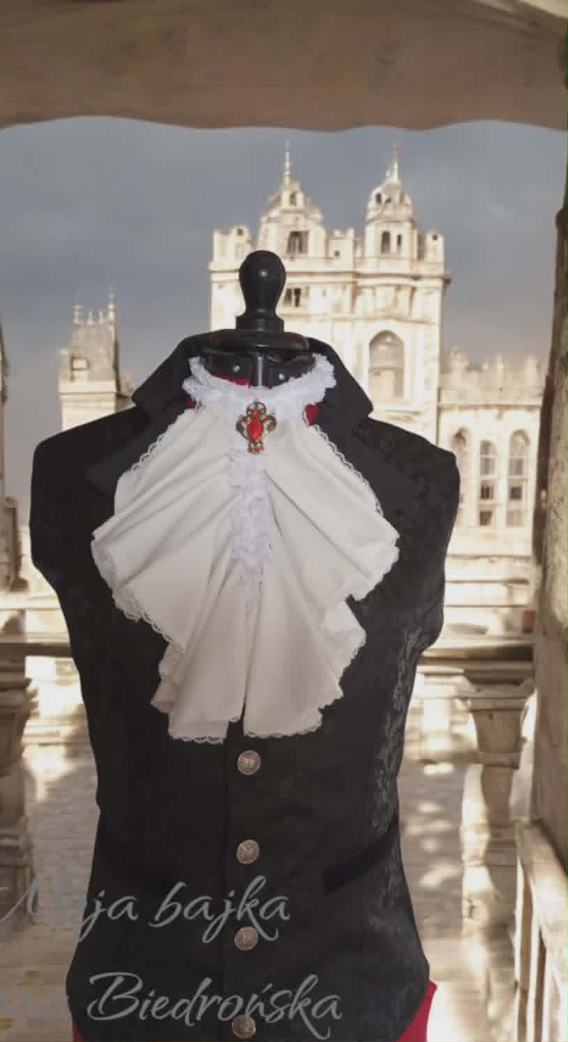 Black dress form displaying white embroidered handkerchief with red cross pendant, with ornate church towers in background