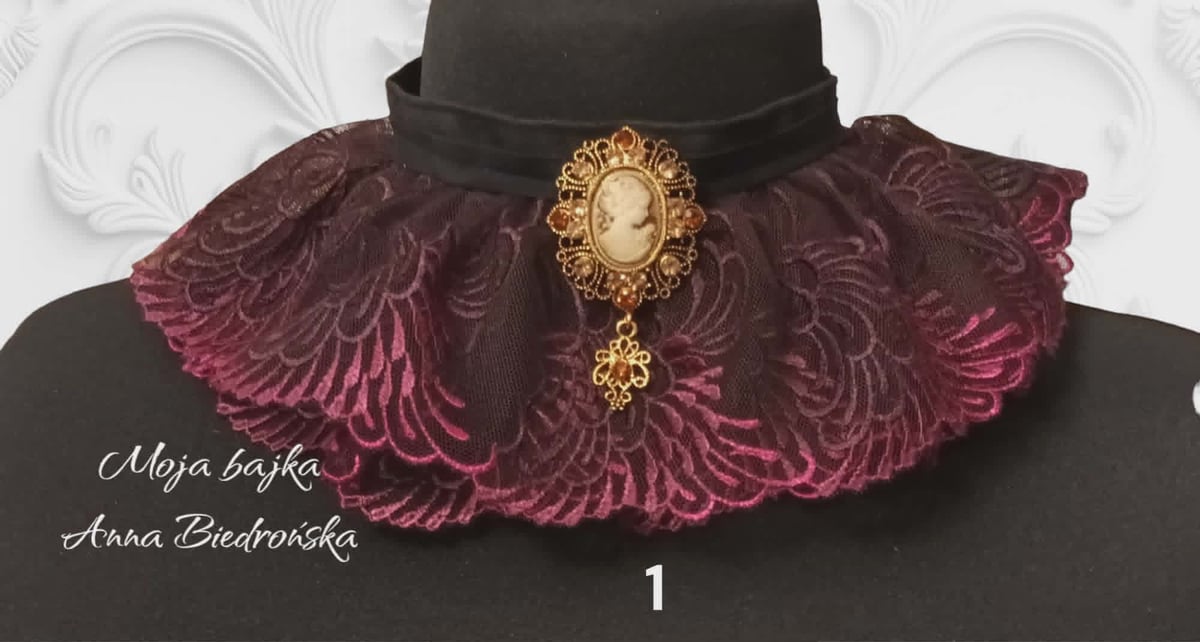Burgundy velvet winged collar with ornate gold cameo brooch, worn over black attire