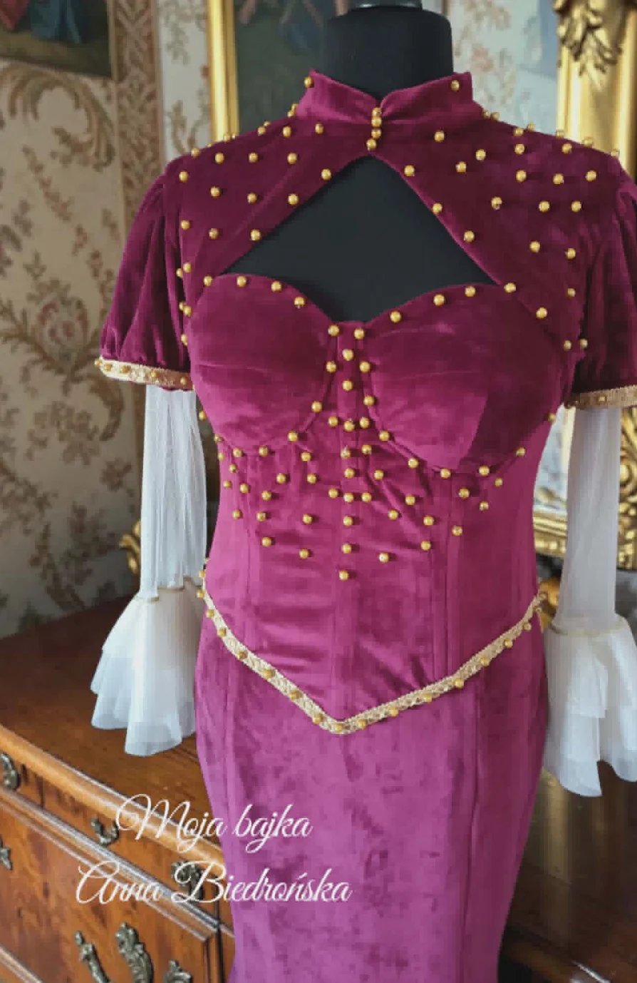 Magenta velvet dress on mannequin with gold beaded embellishment, white puff sleeves, and keyhole back cutout