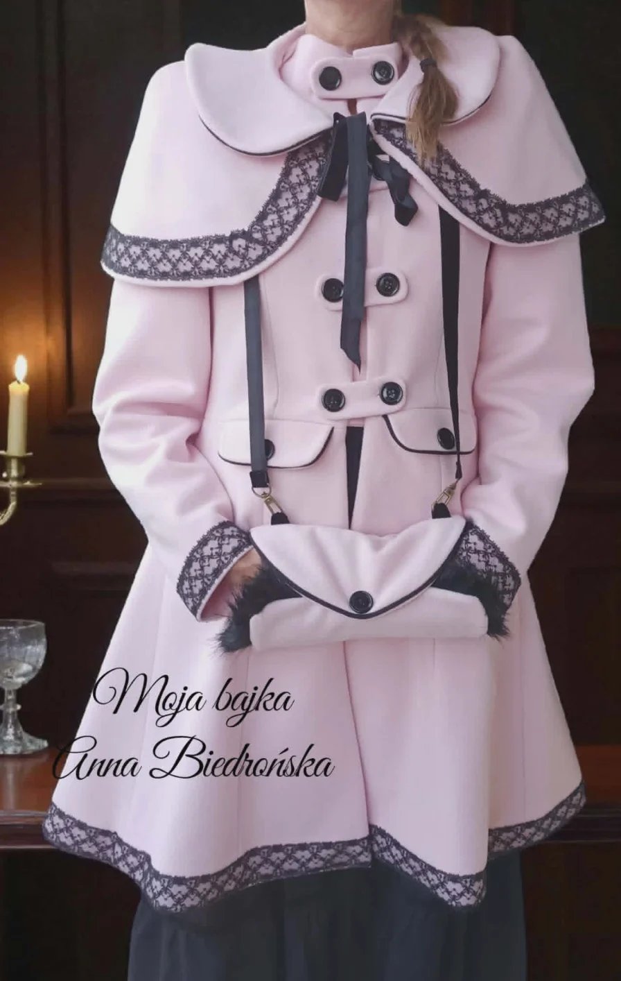Person wearing vintage-style pink coat with white collar, black lace trim, and decorative buttons. Black ribbon bow at neckline. Text overlay reads Moja bajka Anna Biedronska.