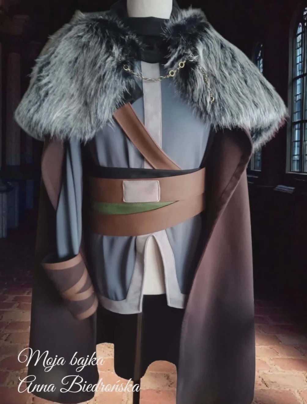 Fashion mannequin wearing a gray and brown ensemble with fur collar and leather belt, displayed indoors