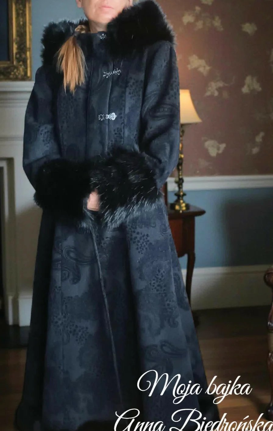 Woman wearing an elegant dark blue ornate coat with black fur collar and cuffs, standing in a formal interior room