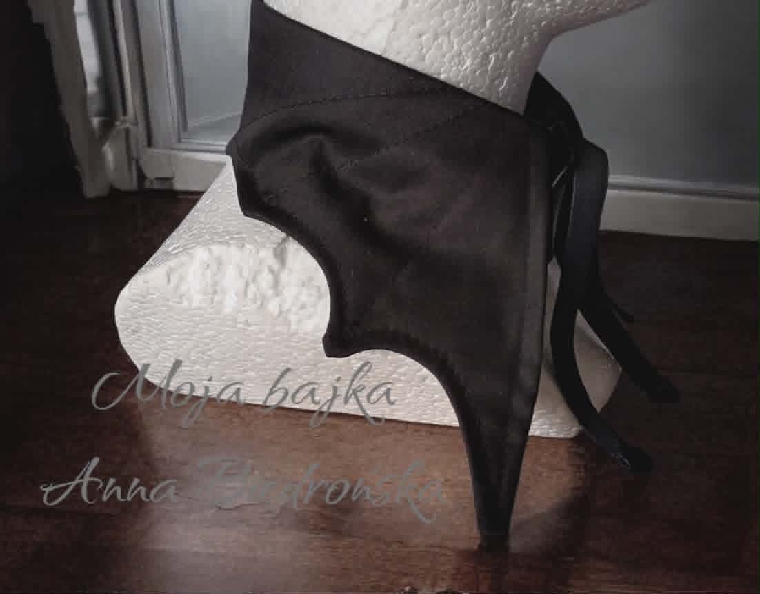 Black chair with white cushions against white wall on dark wooden floor