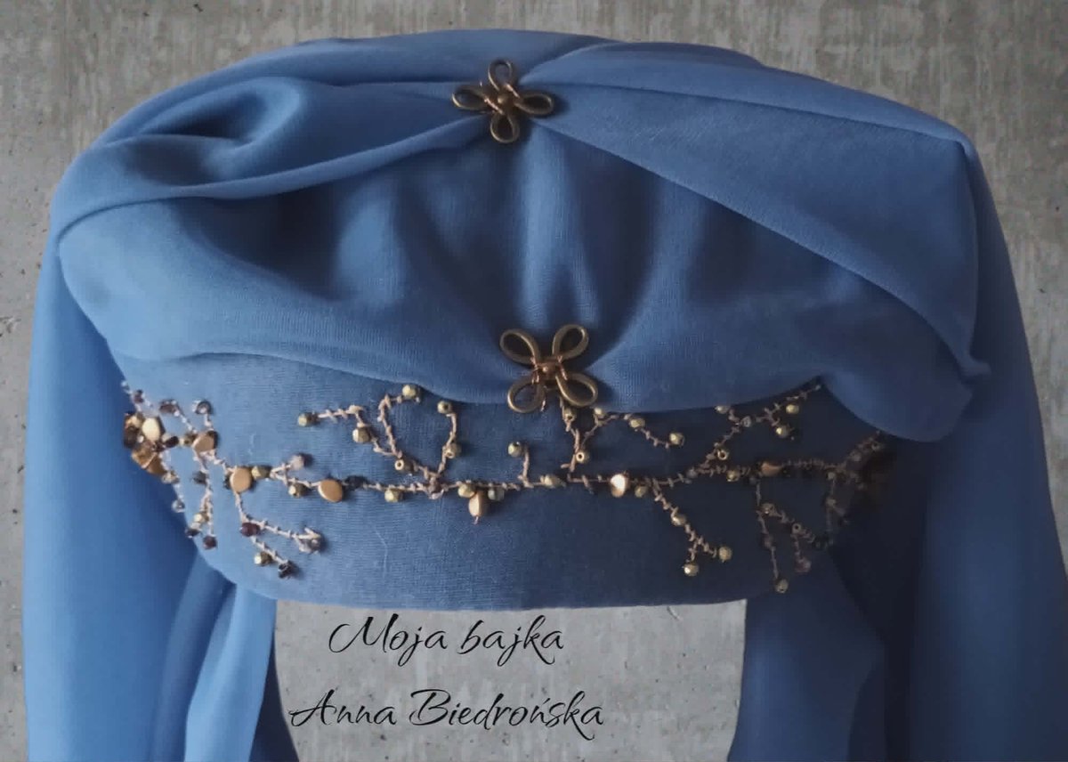 Blue fabric garment with gold beaded decorative patterns and label reading Alicja Bajka and Anna Bedronska