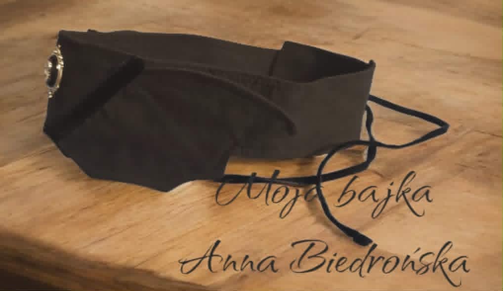 Black fabric shoulder bag on wooden surface with handwritten text overlay reading Aldona Bajka and Anna Biedrońska