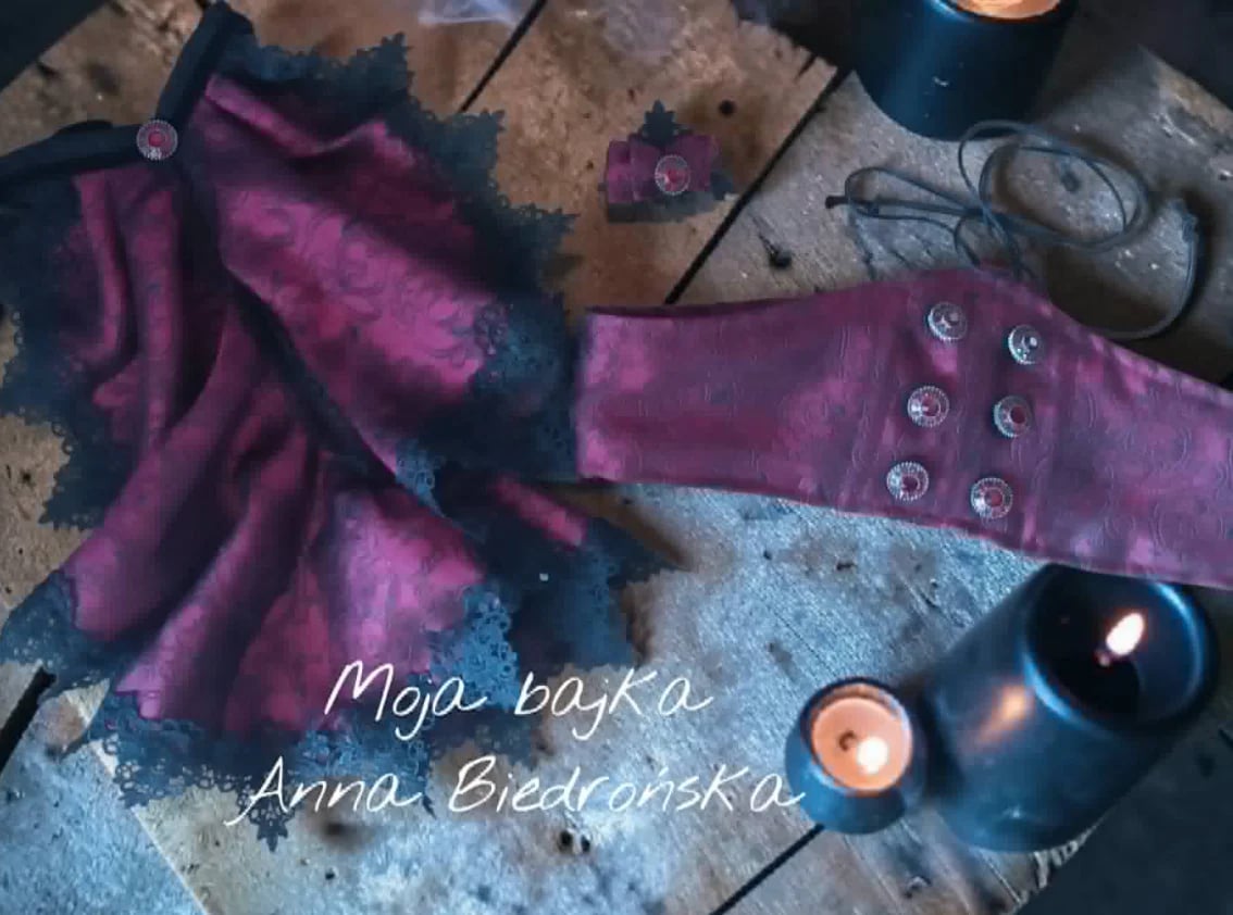 Purple velvet arm cuff with studs on a textured surface surrounded by candles and crystals, with text overlay