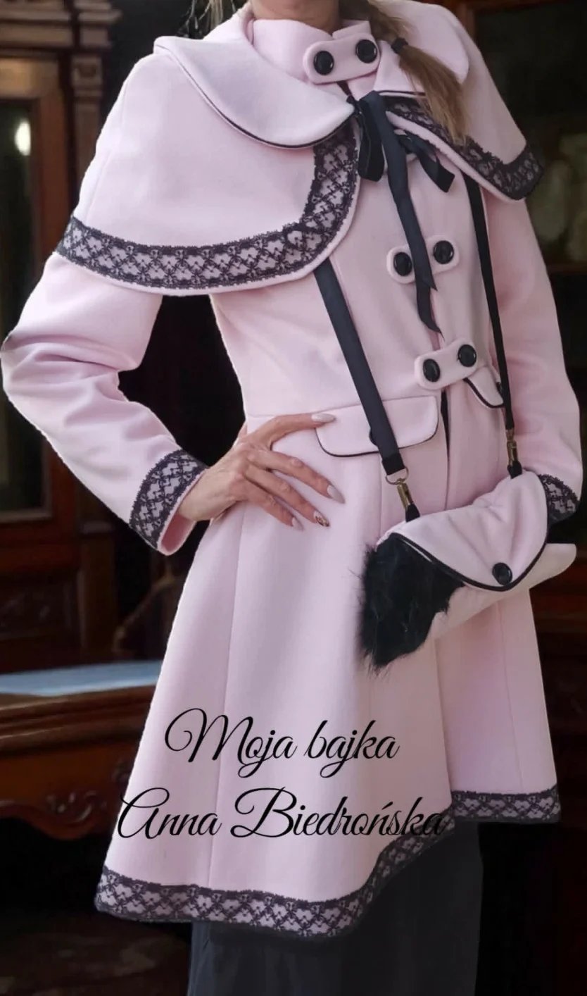 Woman wearing a pink coat with white collar and black lace trim, holding a small black crossbody bag