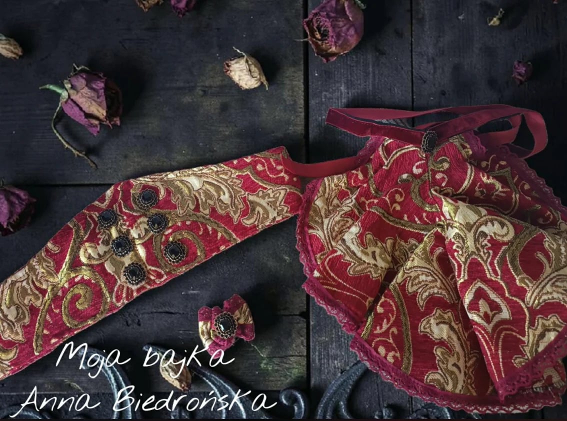 Red and gold ornate fabric pouches on dark wooden surface with dried flowers and handwritten text