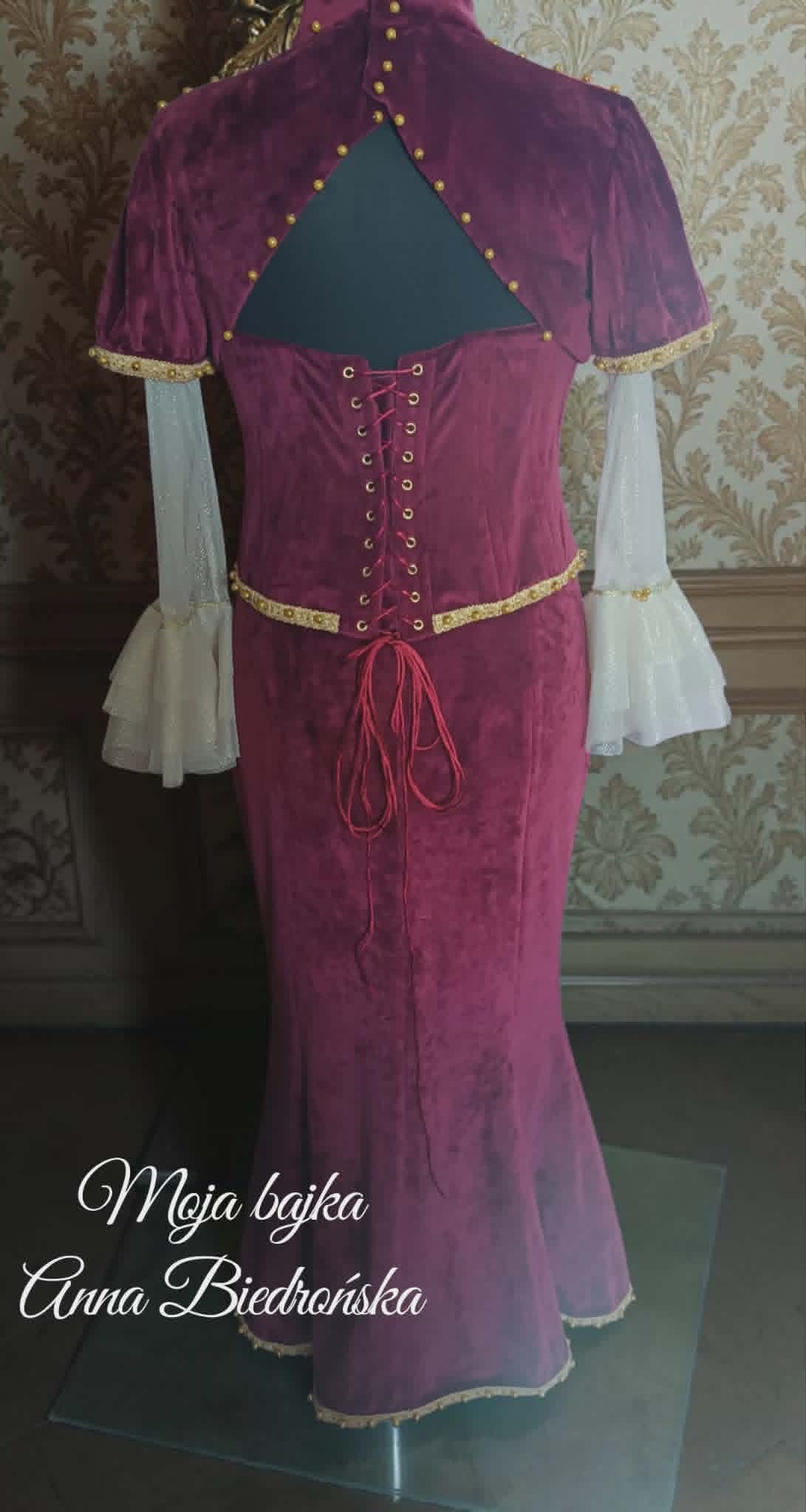 Medieval-style purple velvet dress with short cape, lace-up corset back, white bell sleeves, and decorative gold trim on display