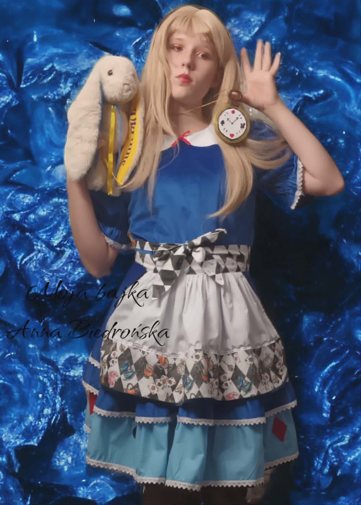 Girl in Alice in Wonderland costume holding white rabbit and pocket watch against blue background