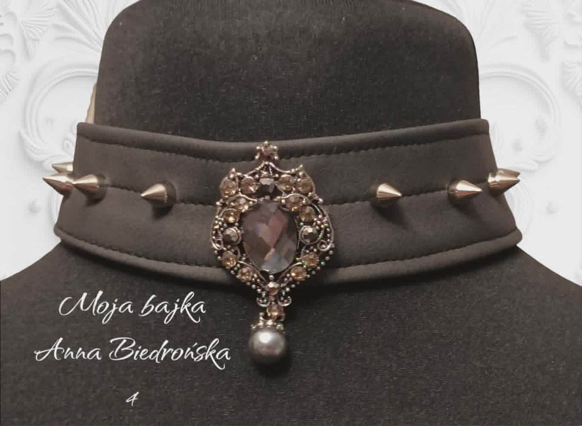 Gray velvet choker necklace with ornate jeweled pendant and spikes on dark mannequin head