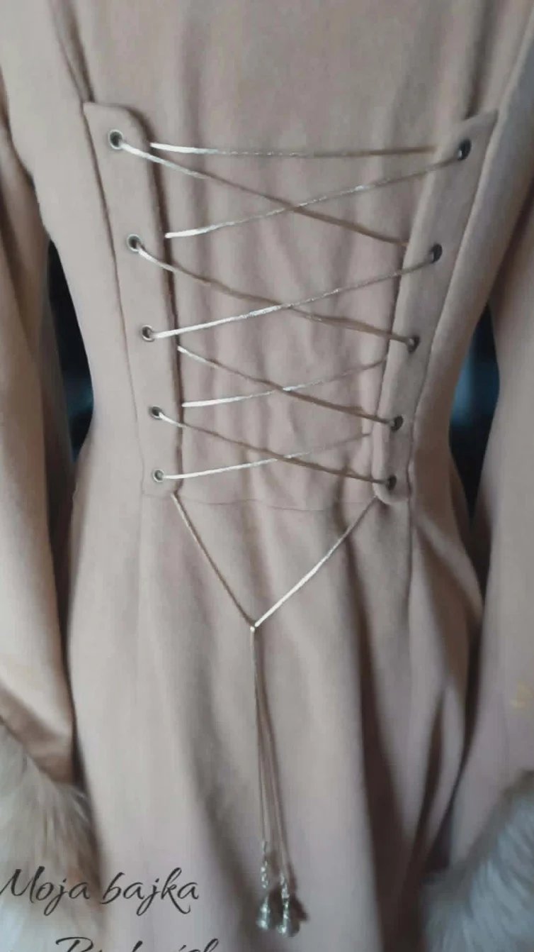Back view of a beige lace-up dress with silver crisscross lacing and eyelet details down the back, tied with drawstrings